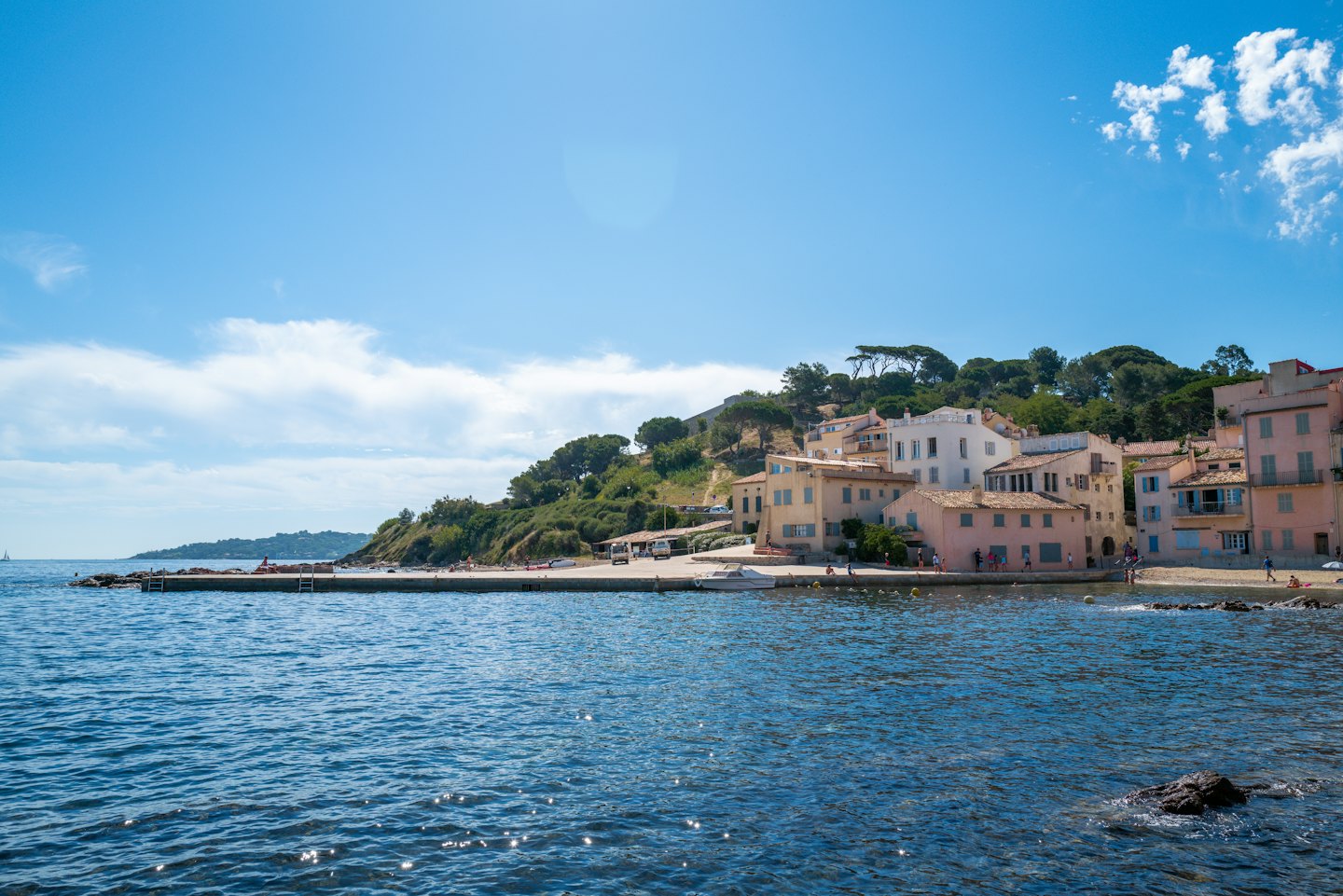 Pastel buildings sit on a hillside overlooking the ocean.