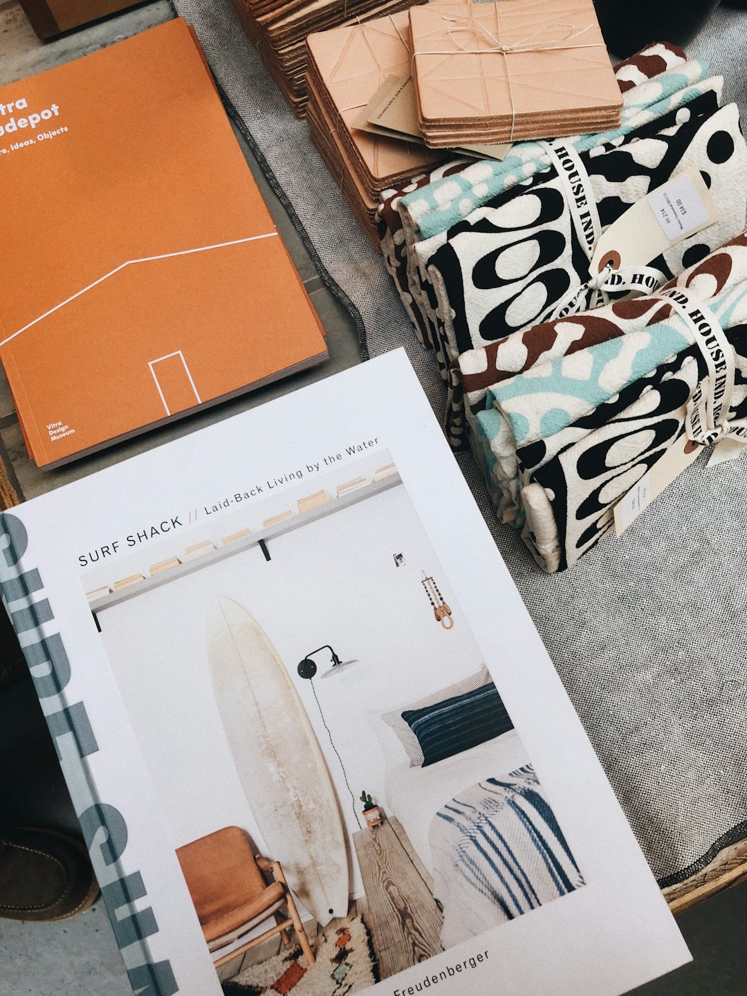 Orange and white books with wooden coasters and patterned textiles.